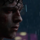 A stunned Peter Parker stands forlornly in the pouring rain.